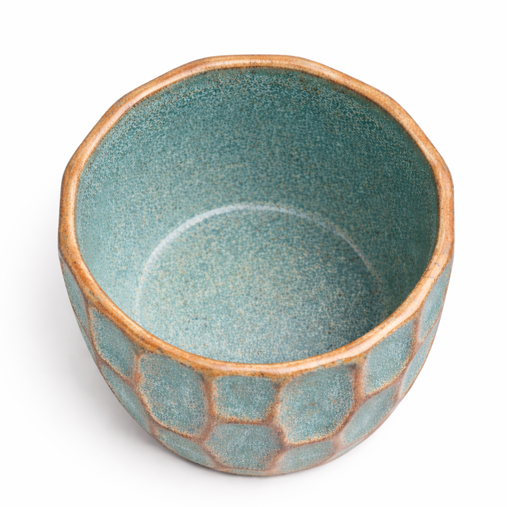 Teal ceramic bowl with geometric pattern on a white background